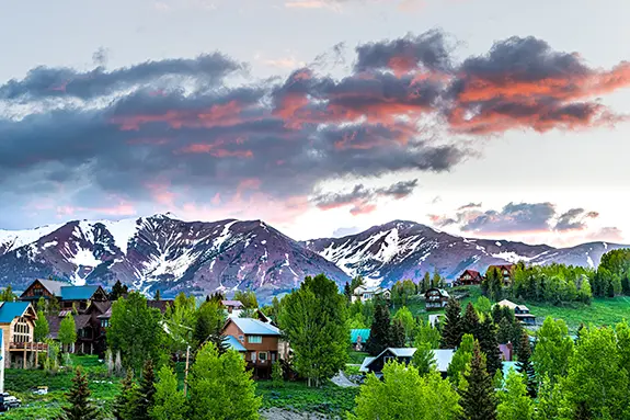 Couple outside mountain home in Colorado surrounded by trees