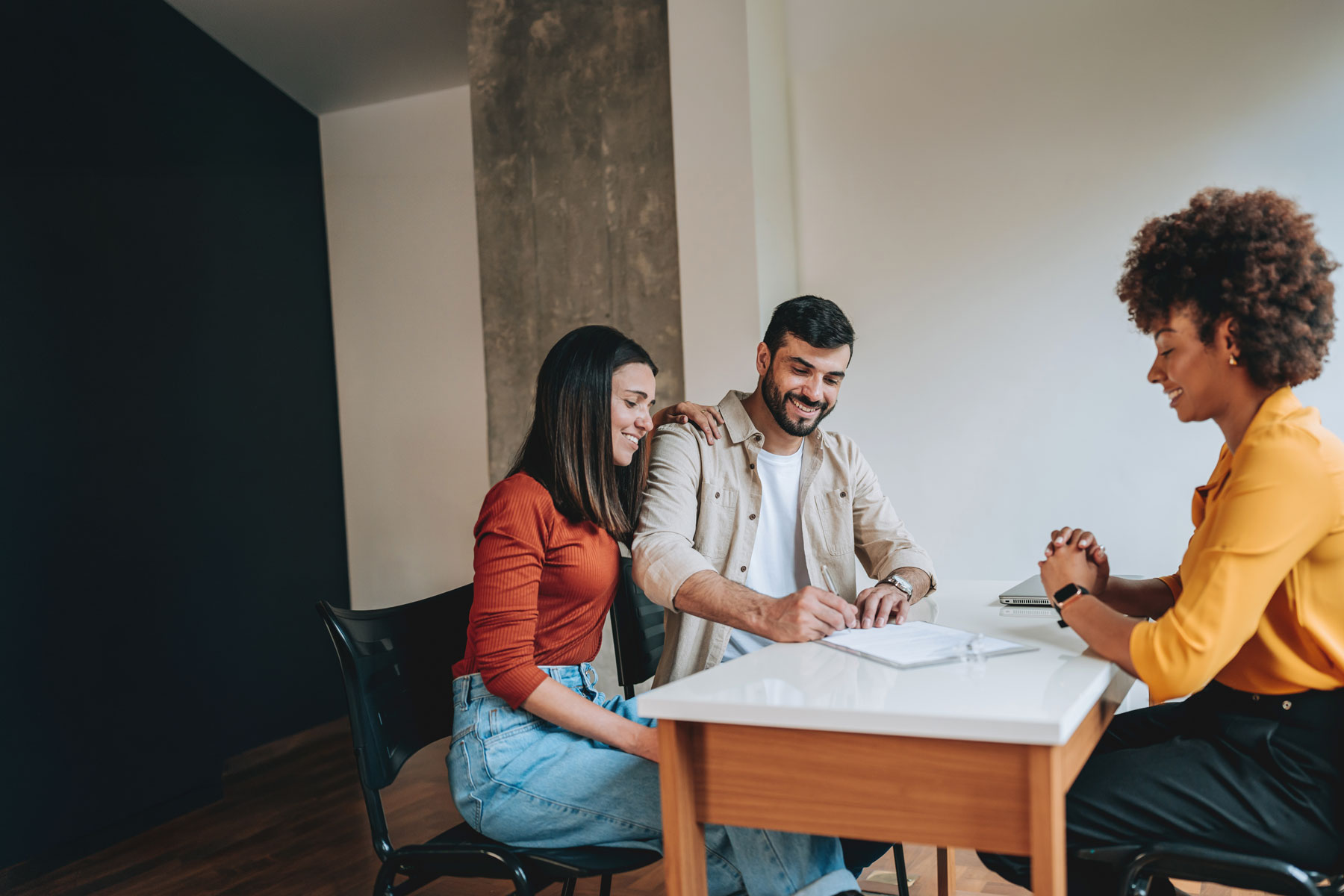 New homeowners meeting with home loan mortgage advisor in an office preparing to buy new home